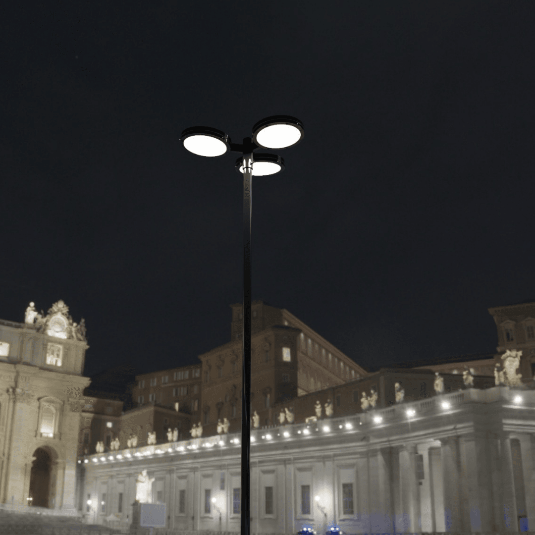 Poste decorativo com três luminárias LED redondas PT 535 em um ambiente noturno com vista frontal, unindo design moderno e alta performance luminosa para jardins, condomínios e espaços públicos.