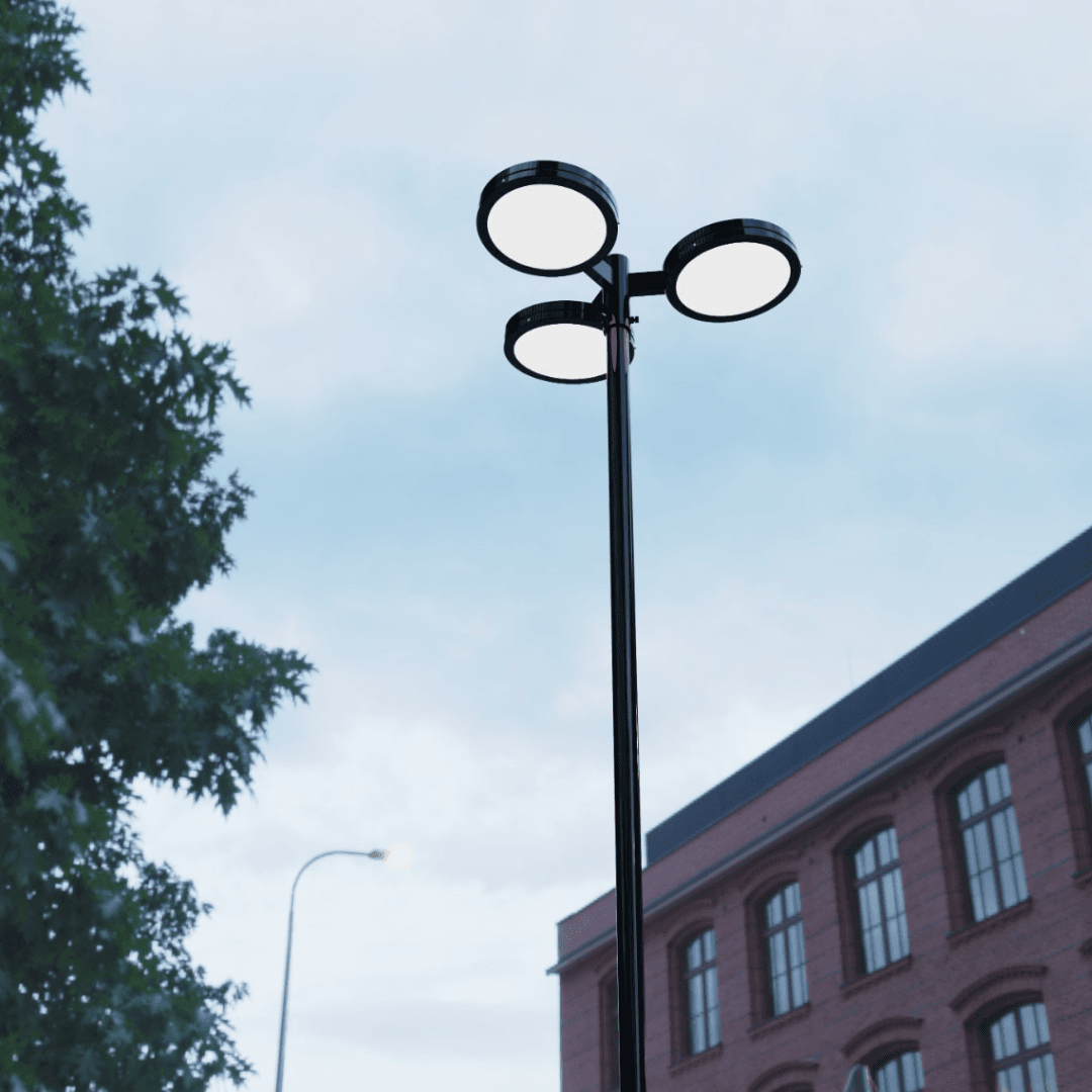 Poste decorativo com três luminárias LED redondas PT 535 em um ambiente de dia com vista frontal, unindo design moderno e alta performance luminosa para jardins, condomínios e espaços públicos.