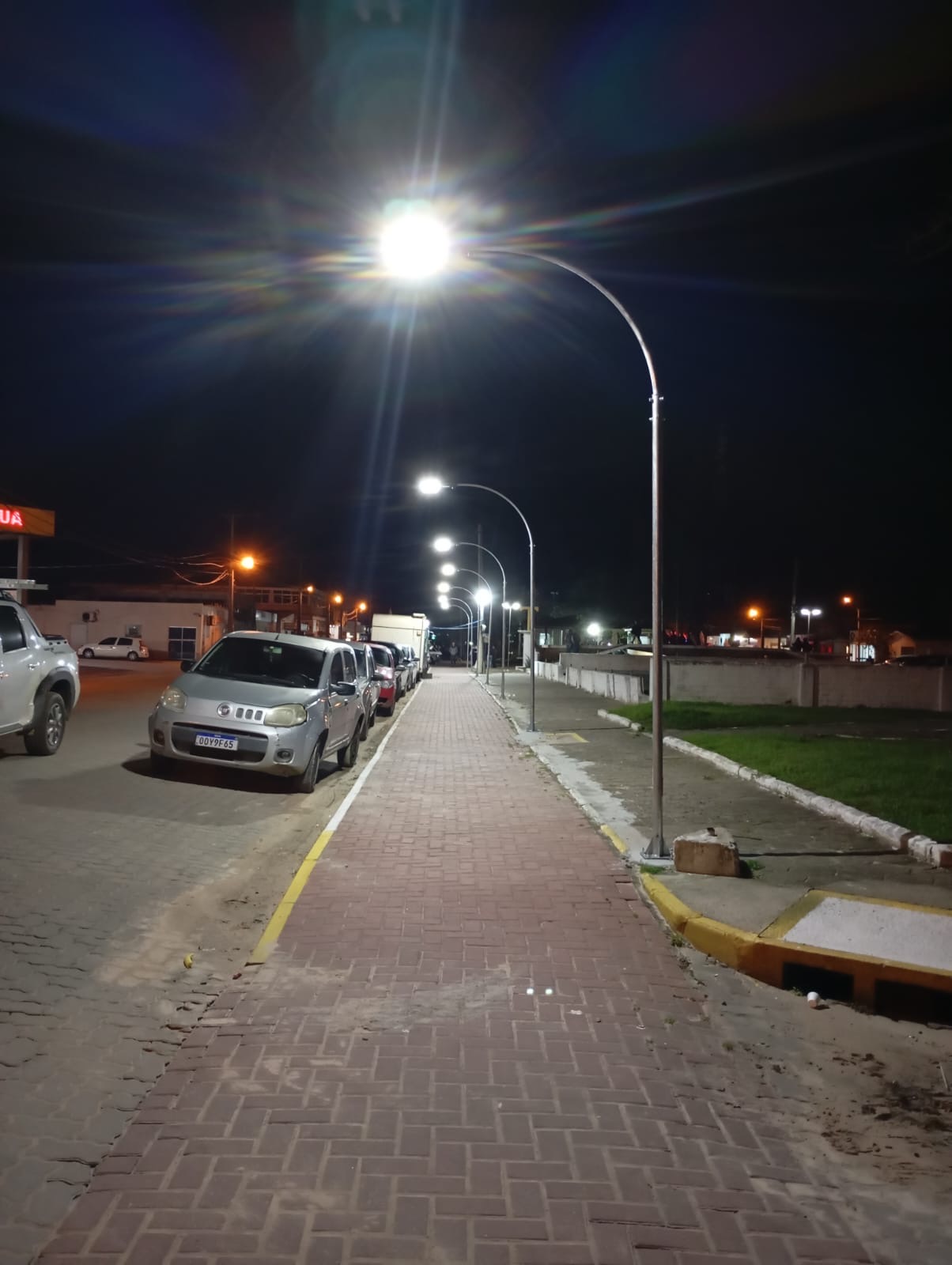 Fotografia real enviada pela Aladin: sequência de postes curvos em rua à noite